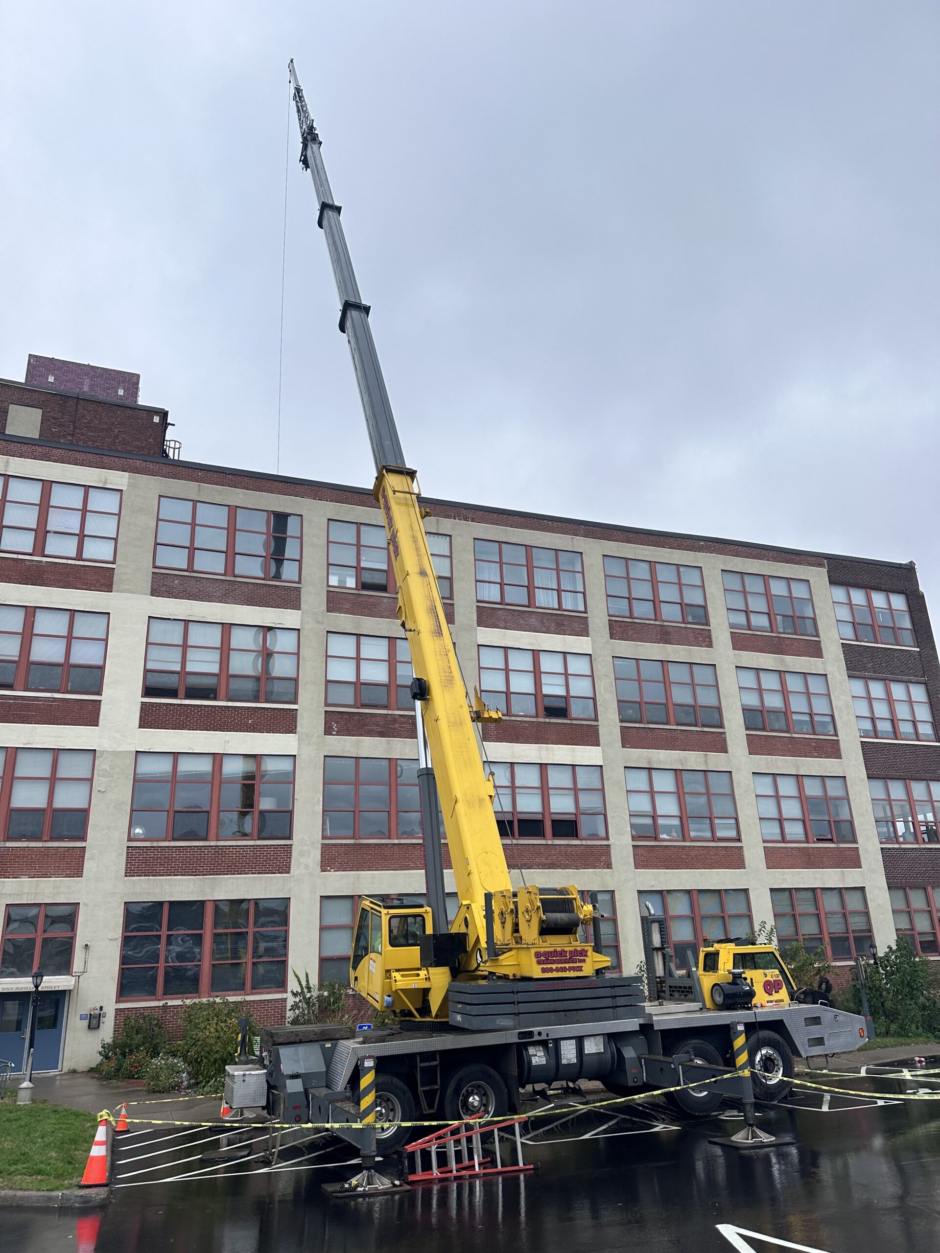 Telescopic boom crane at historic mill building with outriggers deployed