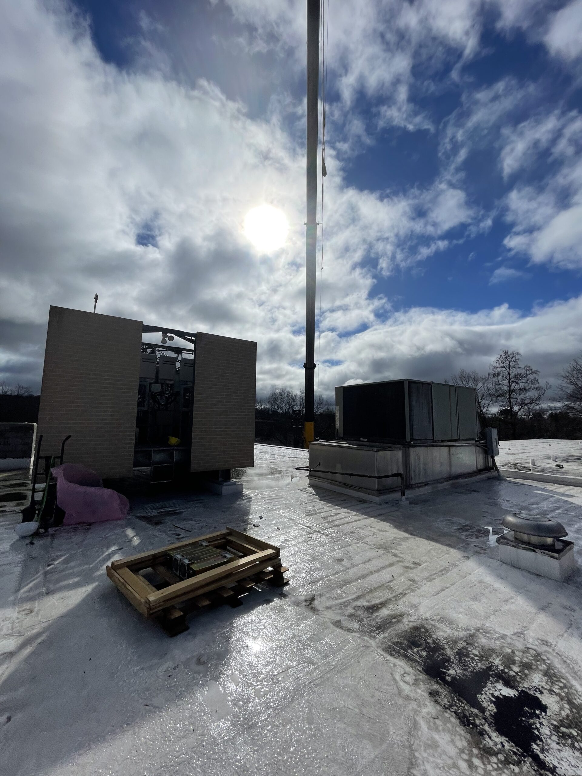 Rooftop HVAC units with crane boom overhead on commercial building